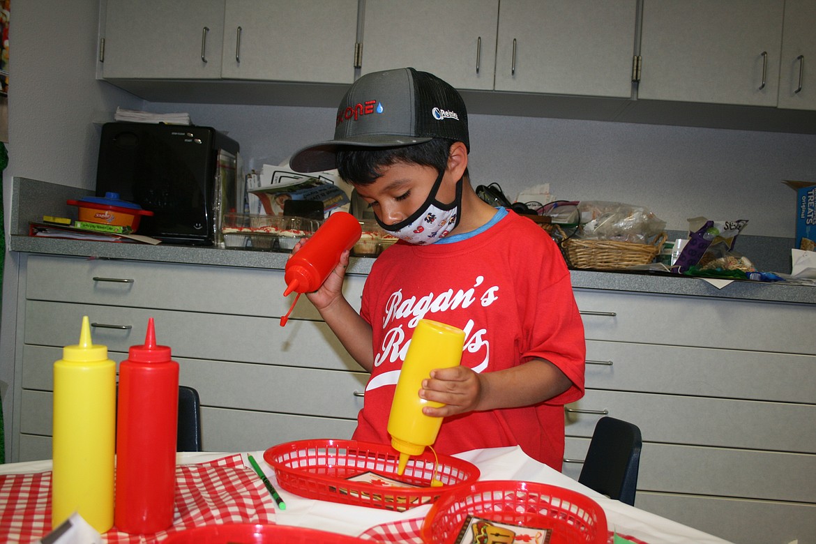 Dean Wilson uses ketchup and mustard bottles to help him sound out a word in the "concession stand" Friday. Peninsula Elementary kindergarten teacher Heidi Ragan turned her classroom into a baseball stadium.