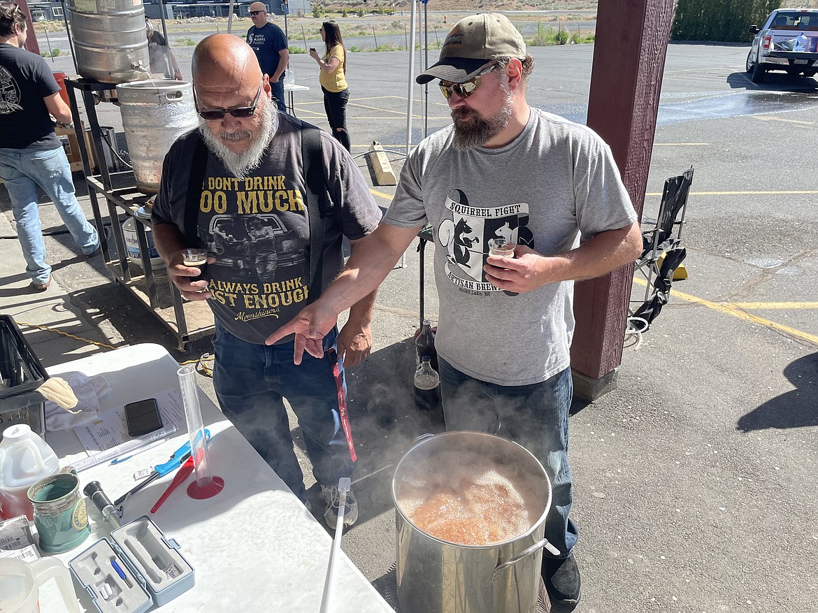 Travis Laibl (right) shows off a piece of brewing equipment to fellow Moses Lake Union of Great Zymurgists (MUGZ) club member Raymond Chavez on Saturday during the club’s commemoration of National Homebrew Day.