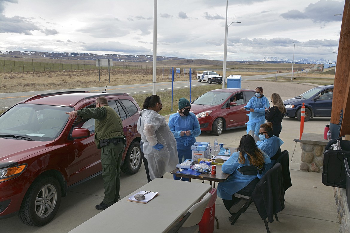 In this Thursday, April 29, 2021, photo, a U.S. Border Patrol agent directs a driver after the passenger received a COVID-19 vaccine from nurses of the Blackfeet tribe at the Piegan-Carway border crossing near Babb, Mont. The Blackfeet tribe in northern Montana gave out surplus vaccines in April to its First Nations relatives and others from across the border. (AP Photo/Iris Samuels)