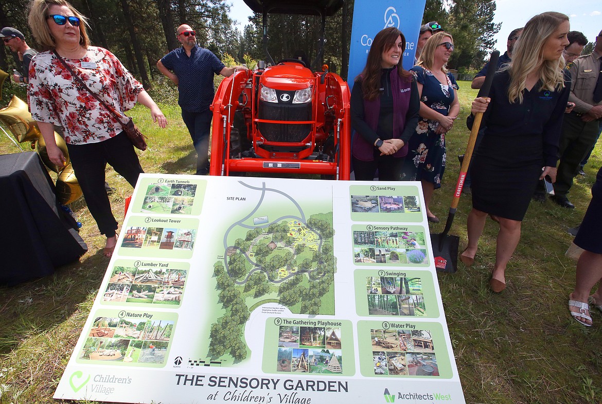 Some of those who attended Wednesday's groundbreaking of The Sensory Garden at Children's Village gather near the site plans created by Architects West.