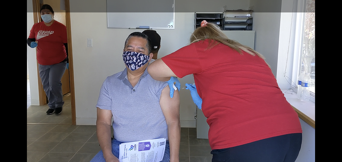 State Representative Alex Ybarra (left) gets his first COVID-19 vaccine shot from Sara Maldonado of Medical Teams International at a mass vaccination clinic Wednesday in Royal City.