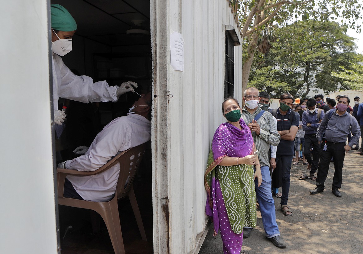 A health worker takes a nasal swab sample of a person to test for COVID-19 as others wait for their turn outside a field hospital in Mumbai, India, Thursday, May 6, 2021. Infections in India hit another grim daily record on Thursday as demand for medical oxygen jumped seven-fold and the government denied reports that it was slow in distributing life-saving supplies from abroad.