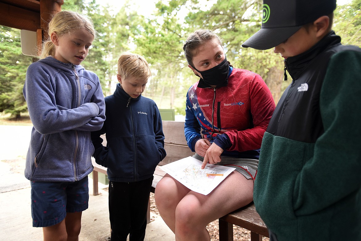 Asher, Anna and Brooks Stanfield of Kalispell receive a crash course in orienteering from Team USA member Caroline Sandbo at Lone Pine State Park Sunday. (Jeremy Weber/Daily Inter Lake)