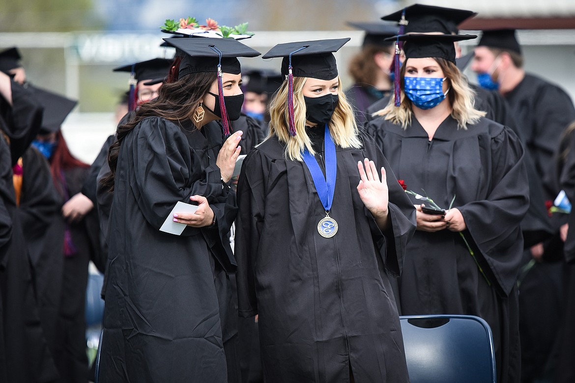 A pair of graduates wave before taking their seats during the Flathead Valley Community College commencement ceremony at Legends Stadium on Friday. (Casey Kreider/Daily Inter Lake)