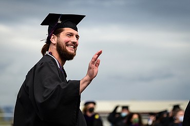 A graduate waves towards the crowd before taking his seat at the Flathead Valley Community College commencement ceremony. (Casey Kreider/Daily Inter Lake FILE)