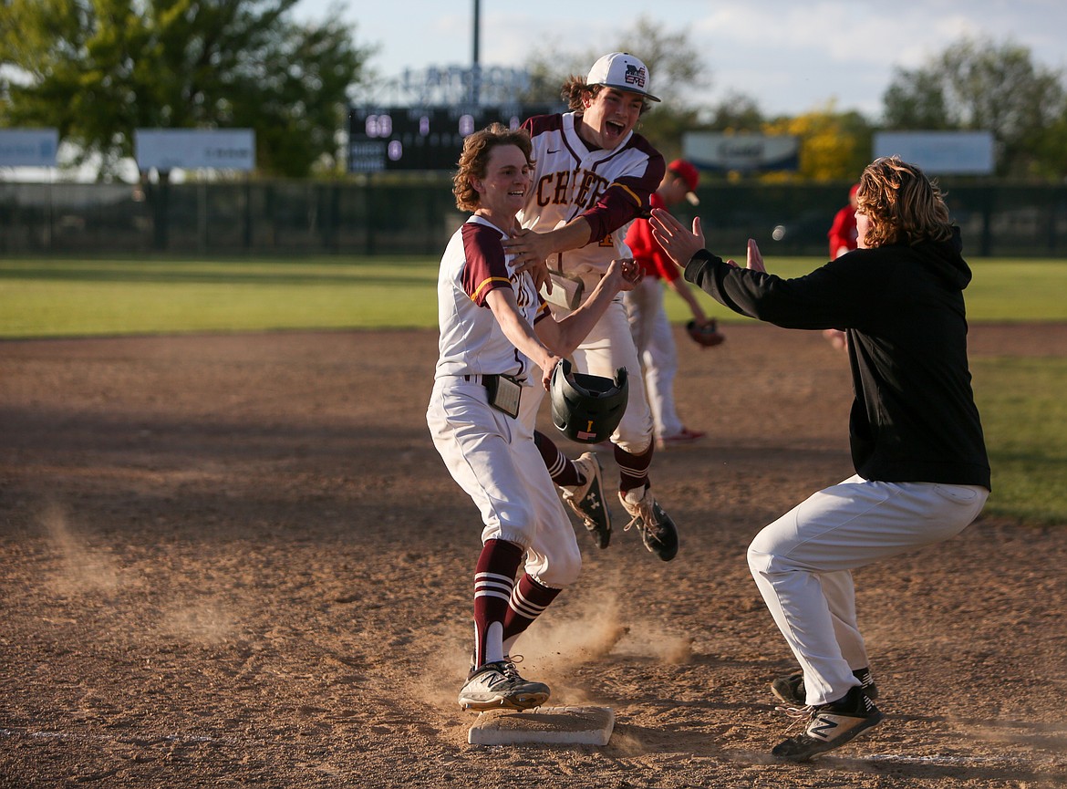 Moses Lake High School's Blaine Macdonald is met by his teammates at third base after Macdonald brought in the winning run for the Chiefs in the bottom of the eleventh inning on Friday afternoon in Moses Lake.