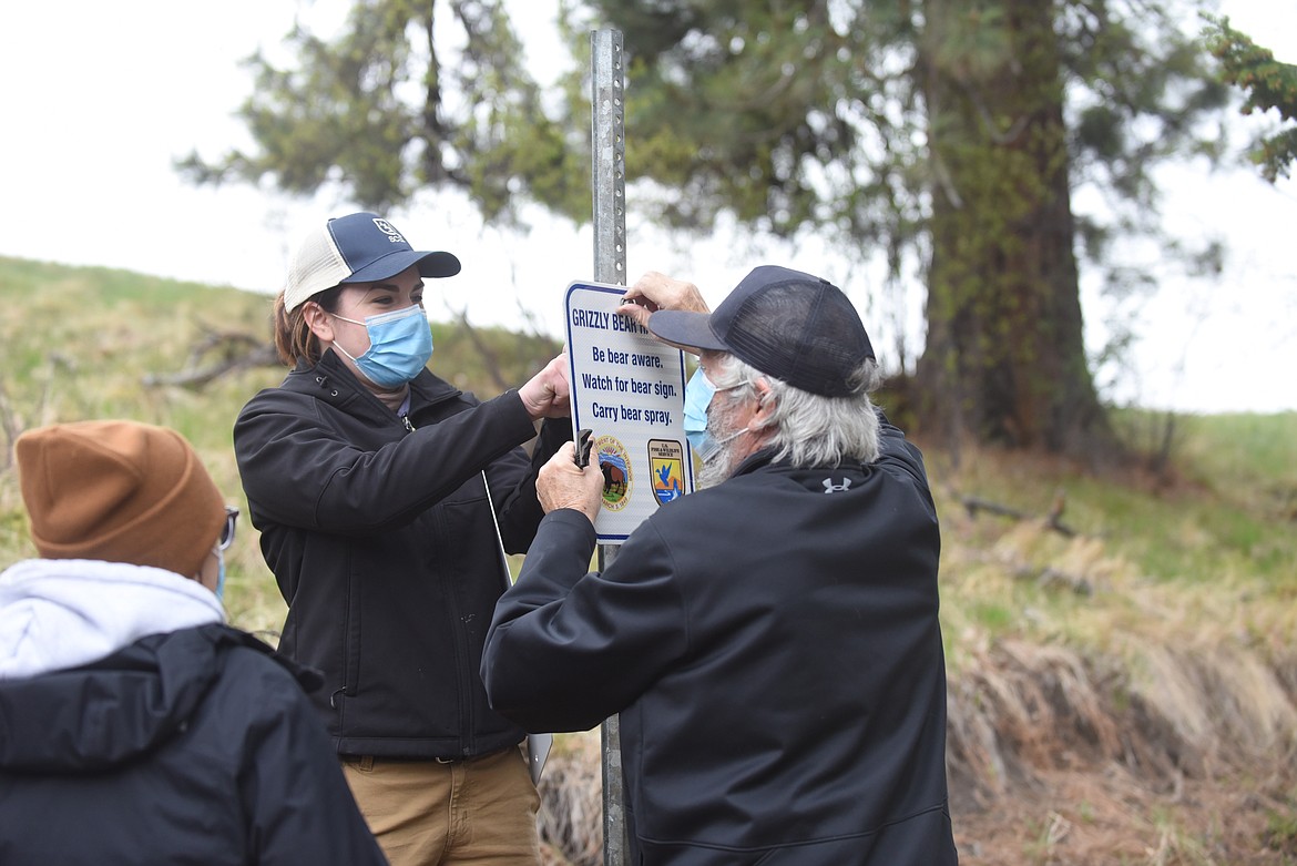 Summer employee Hannah Bancroft and volunteer Dave Fitzpatrick put up a sign warning visitors about the possibility of encountering a grizzly bear while Bison Range park aide Mariah Durglo watches Saturday. (Scott Shindledecker/Valley Press)