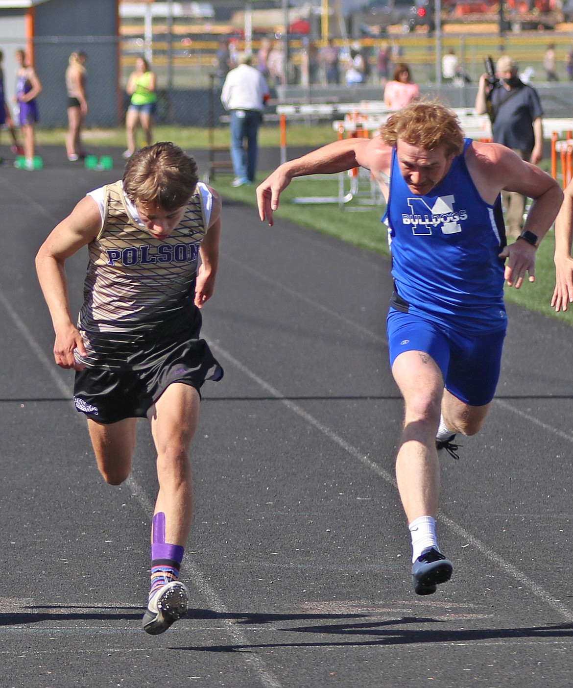 Lucas Targerson of Polson leans for the win in the boys 100 meters next to second-place finisher Charles Adams of Mission. Targerson ran the event in 11.48 seconds, while Adams came in at 11.56. (Courtesy of Bob Gunderson)