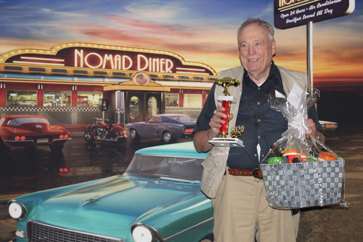 William Snell shows off his trophy in front of a classic diner backdrop after winning best poker hand at the 2020 Silver Angels for the Elderly Classic Car Poker Run. This year's event is May 22.