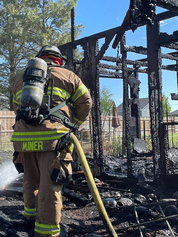 Moses Lake firefighter Mike Miner tends to the structure fire in the 3000 block of Lakeshore Drive Tuesday morning.