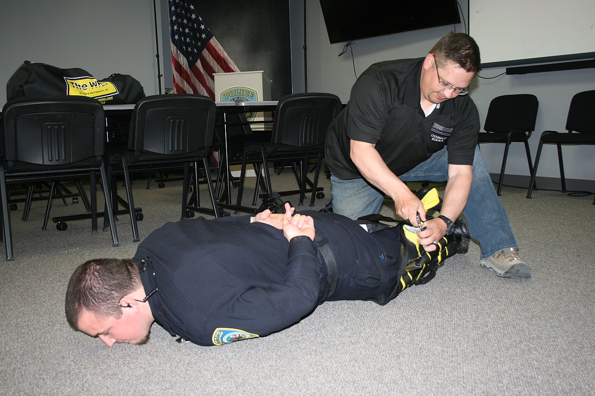 Othello Police Department Sgt. Sean Anderson (kneeling) and OPD officer Martin Garza (on the floor) demonstrate the department’s new restraint system.