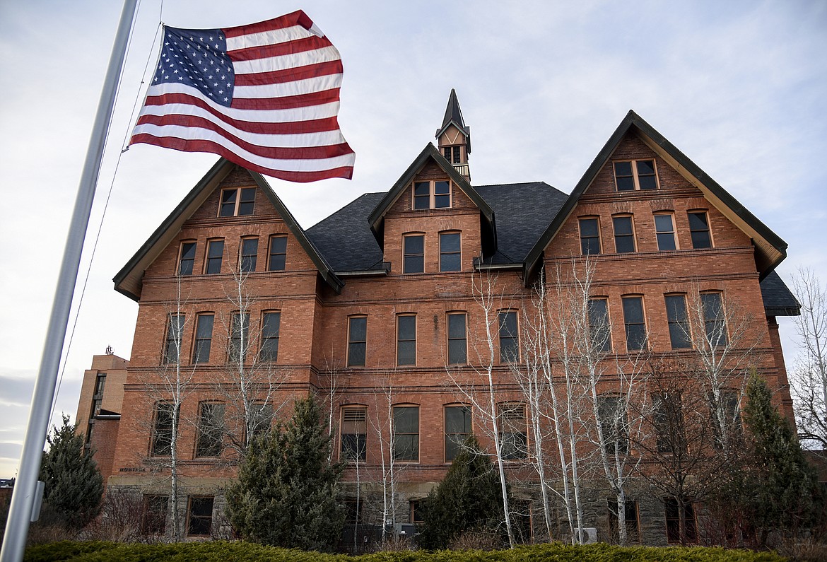 In this April 2, 2021 file photo, a U.S. flag flies at half staff in front of Montana Hall at Montana State University in Bozeman, Mont., in honor of the victims of an attack at the U.S. Capitol that day. The Montana University System has prepared a draft policy for allowing students and others to carry concealed weapons on public campuses in Montana as long as they have firearms safety training and keep the weapons holstered, with an exception for self-defense. Students would have to keep weapons in locked storage in campus housing. A committee of the Montana Board of Regents will hear public comment on the proposed policy on Wednesday, May 12. The Board of Regents will consider the comments and vote on the policy later this month. (Rachel Leathe/Bozeman Daily Chronicle via AP, File)