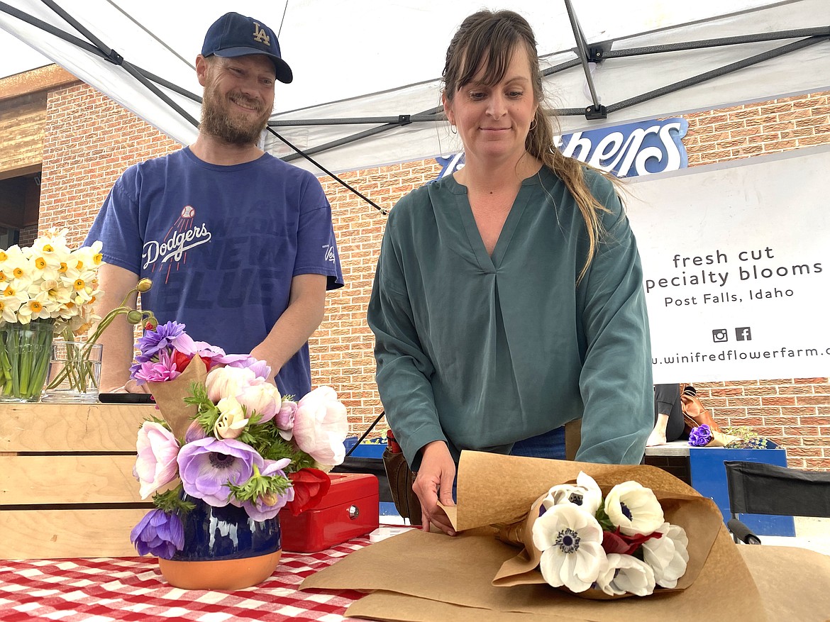 Kendra, right, and Adam Boots, grin ear-to-ear while wrapping up a bouquet of their Winifred Farms heirloom flowers at the farmers' market Wednesday afternoon. (MADISON HARDY/Press)
