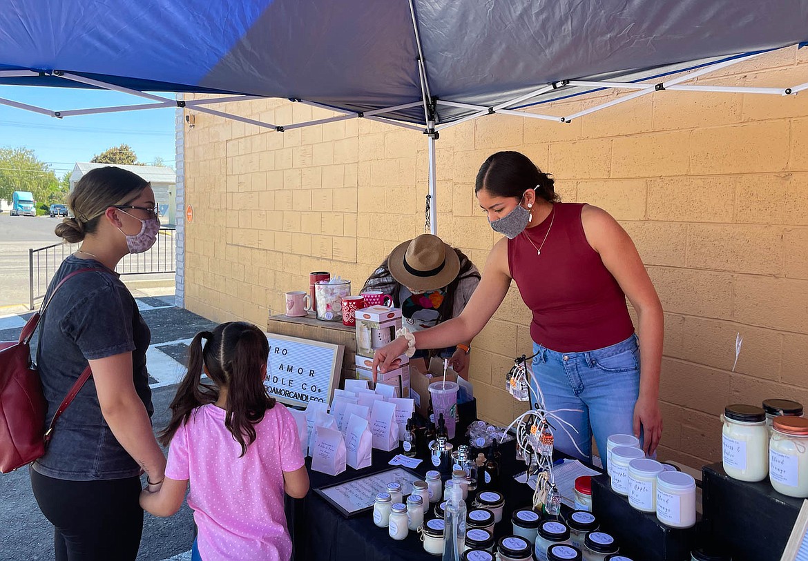 Claudia Valenzuela of Puro Amor Candles helps customers at the She Se Puede Pop Up in Quincy in May.