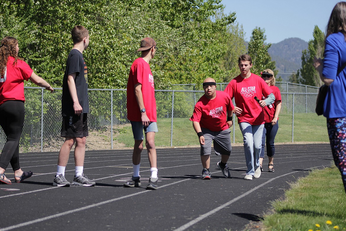 Bradey Scrimsher passes the baton to Corban Caralis at the All Star Olympics Friday.