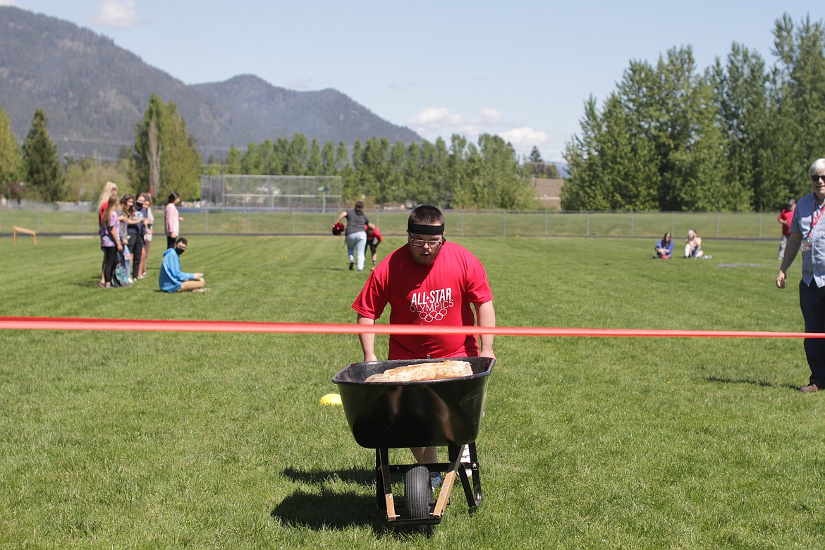 Kevin Collins pushes a wheelbarrow at the All Star Olympics obstacle course.