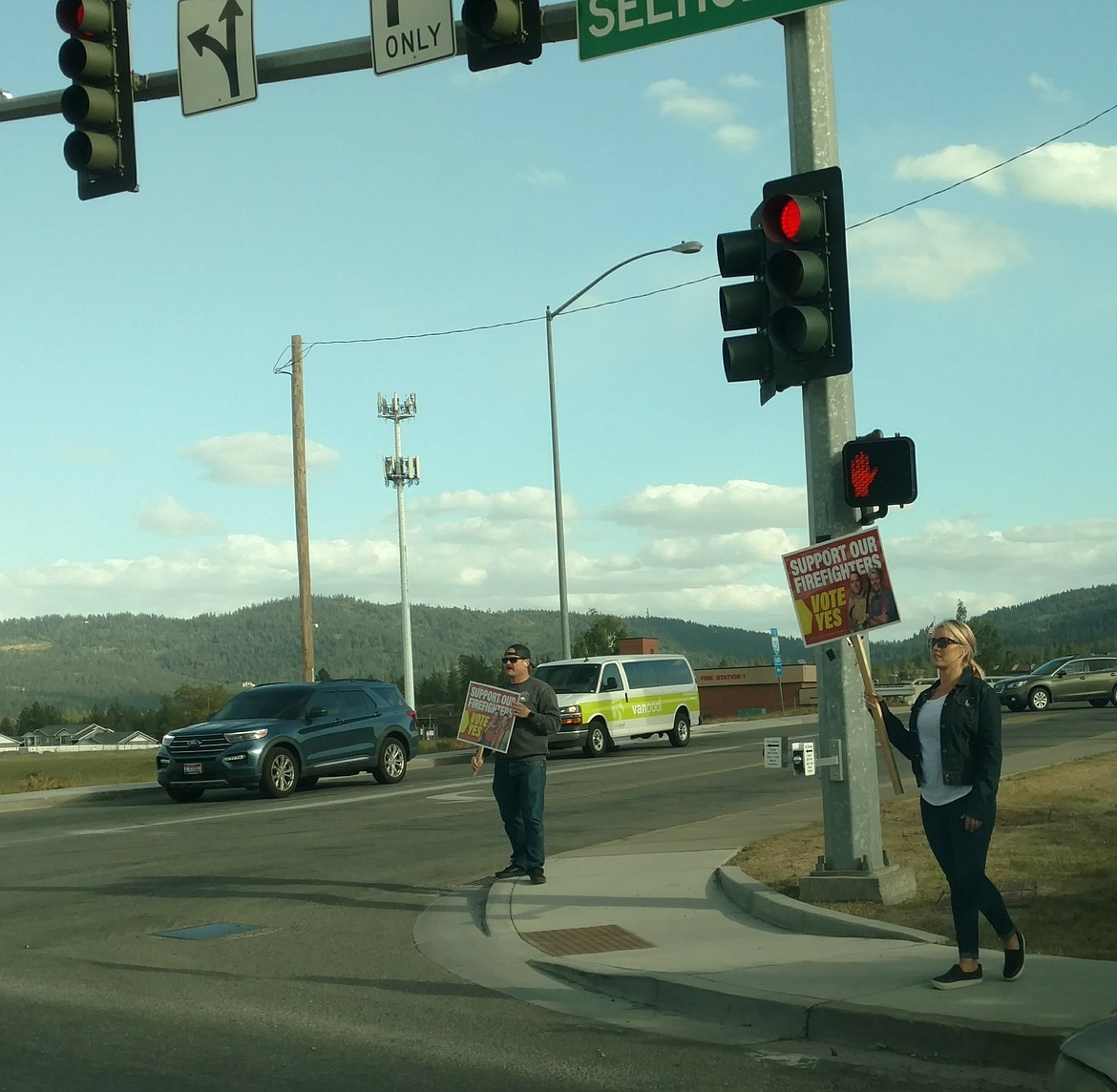 Kootenai County Fire and Rescue supporters hold up signs Tuesday evening at Seltice Way and Idaho Street in Post Falls.