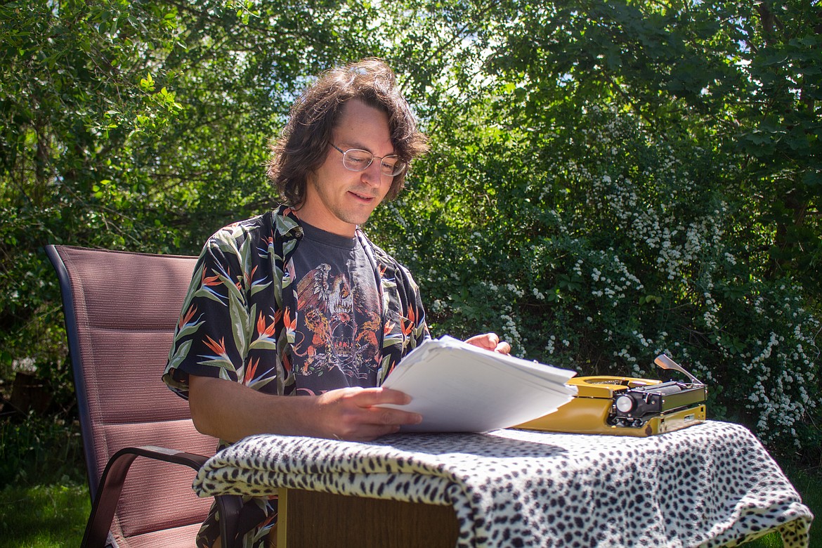 Jeff Ames holds up a collection of his writings in one of his favorite writing spots in his backyard in Moses Lake on Tuesday afternoon.