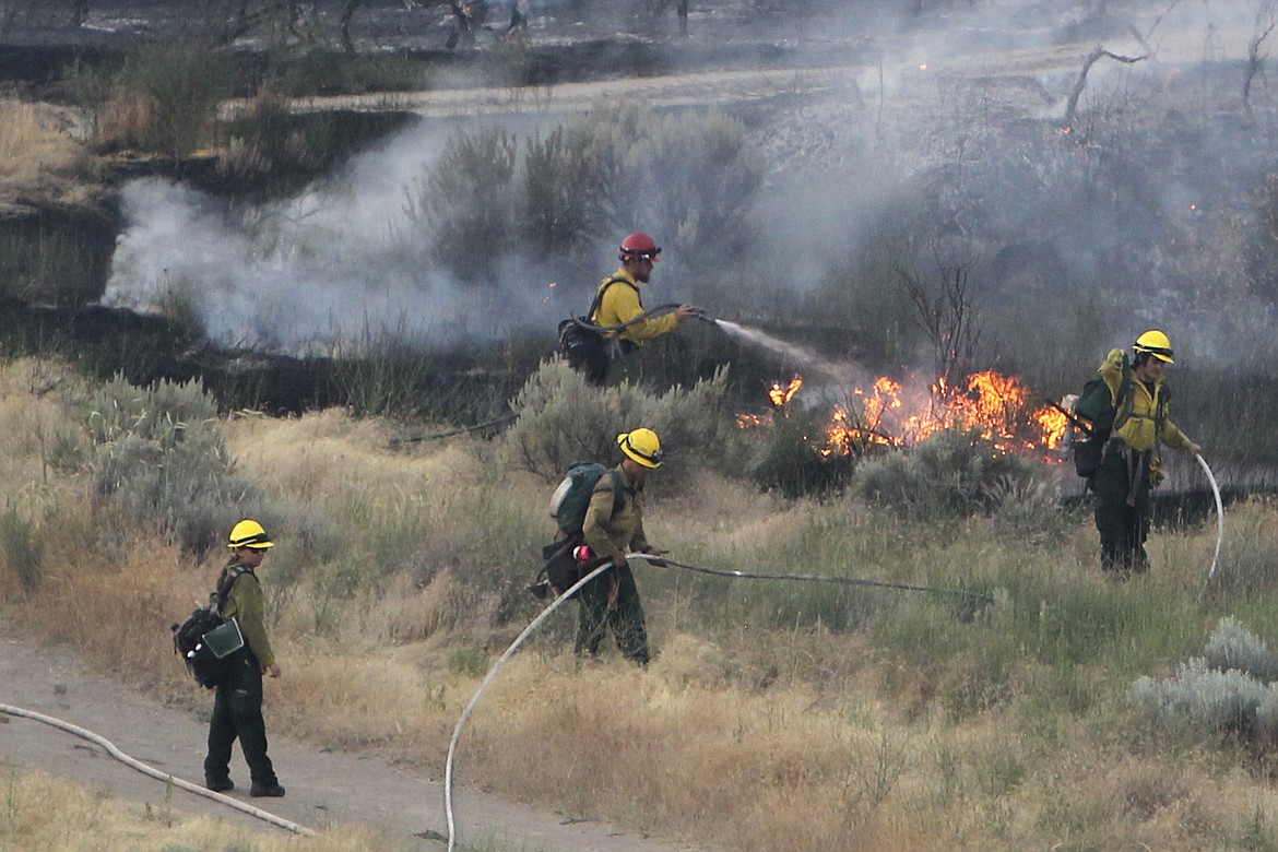 In this June 30, 2016 file photo firefighters respond to a wildfire near the Morningside Heights neighborhood near Table Rock in east Boise, Idaho. With a potential ferocious wildfire season ready to ignite across the western U.S., the push is on to persuade state and federal wildland firefighters to get vaccinated against COVID-19. Republican Idaho Gov. Brad Little said Tuesday, May 18, 2021, that lives could be lost if frontline firefighters get sidelined with the illness.