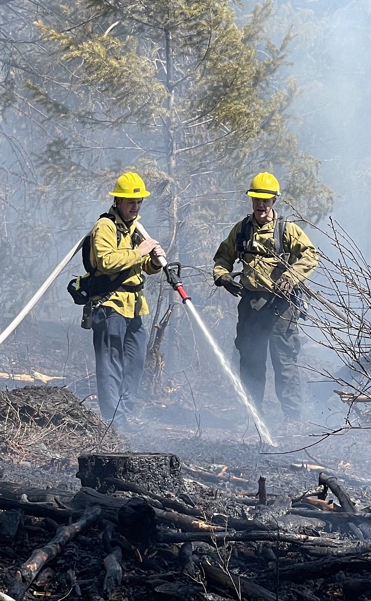 Photo courtesy Timberlake Fire 
Ben Kaplan of Timberlake Fire and Ethan Colby of Selkirk Fire battle a slash fire that recently spread into timber land off Highway 53.