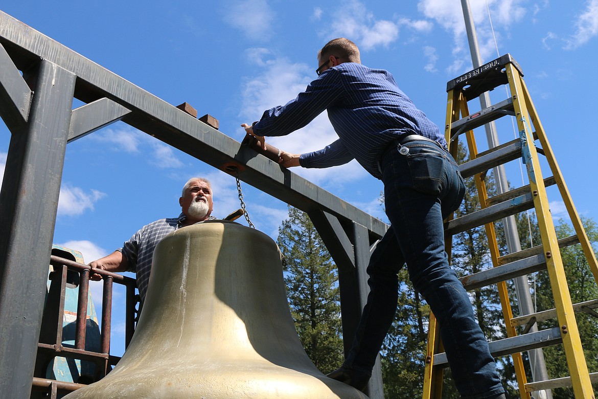 Fred Dehn and Luke Hedquist work to secure the bell in place.