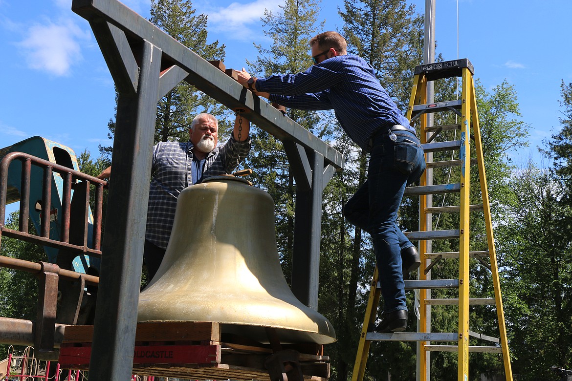 Fred Dehn and Luke Hedquist maneuvering the city's historic bell into place at its temporary home outside Bonner County Historical Museum.