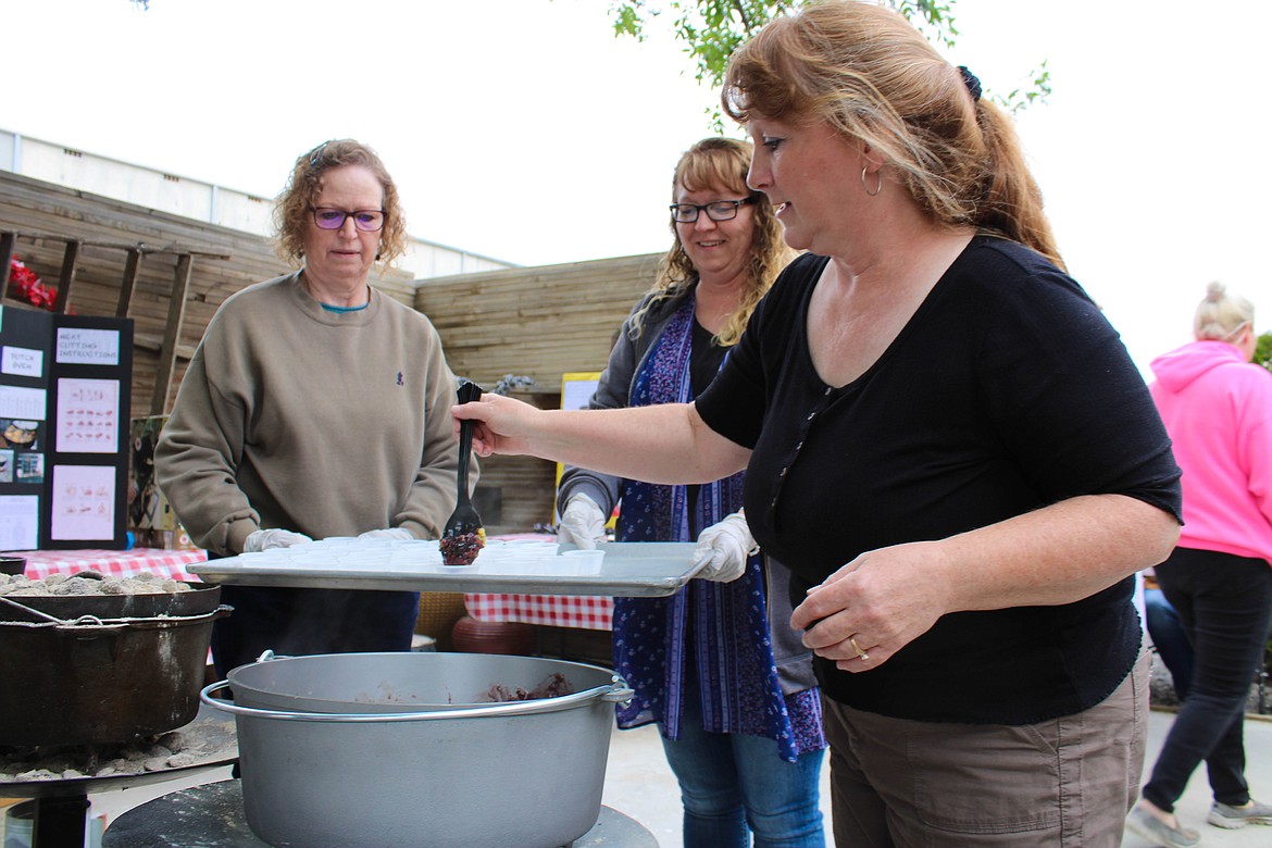 Volunteer Heide Manley (right) prepares berry cobbler samples from a cast iron dutch oven at the Be Ready Expo on Saturday.