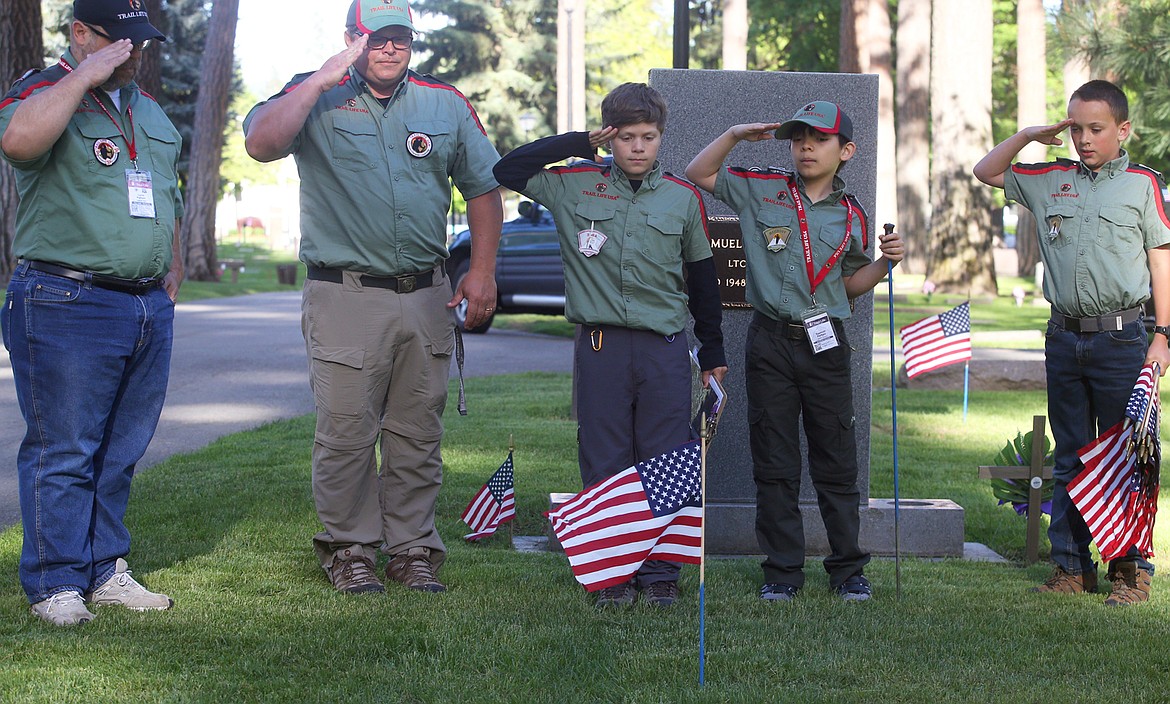 Trail Life USA adult leaders and scouts salute a flag planted at the gravesite of a veteran Wednesday at Forest Cemetery. From left, Lorin Partain, Eddie Bateman, Sawyer Bateman, Spencer Partain and William Gant.