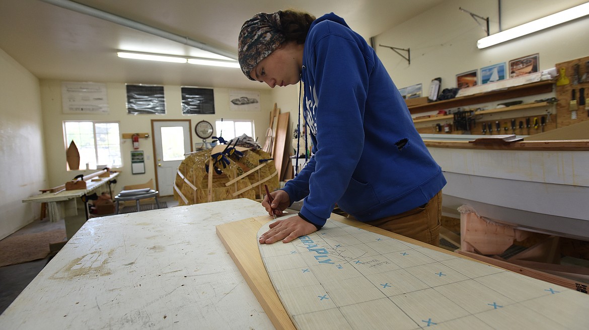 Thirteen-year-old Jake Milone, who is leading his parents through the construction of a Norwegian-style sailboat, traces a pattern for the rudder of on Wednesday, May 26, 2021, at the Montana Wooden Boat Foundation in Lakeside. (Jeremy Weber/Daily Inter Lake)