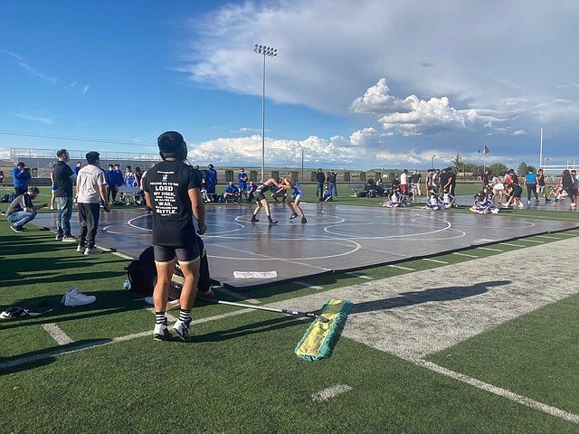 Wrestlers and coaches surround the mat outside on the football field at Royal High School on Tuesday night as Royal, Ephrata, Othello and Warden High School came together for a triple dual event.