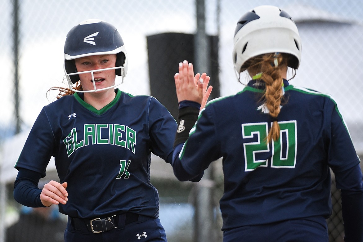 Glacier's Alli Kernan (11) and Kenadie Goudette (20) high five after Kernan scored on a two-run single by teammate Sammie Labrum (10) against Helena during the State Class AA Softball Tournament at Kidsports Complex on Friday. (Casey Kreider/Daily Inter Lake)