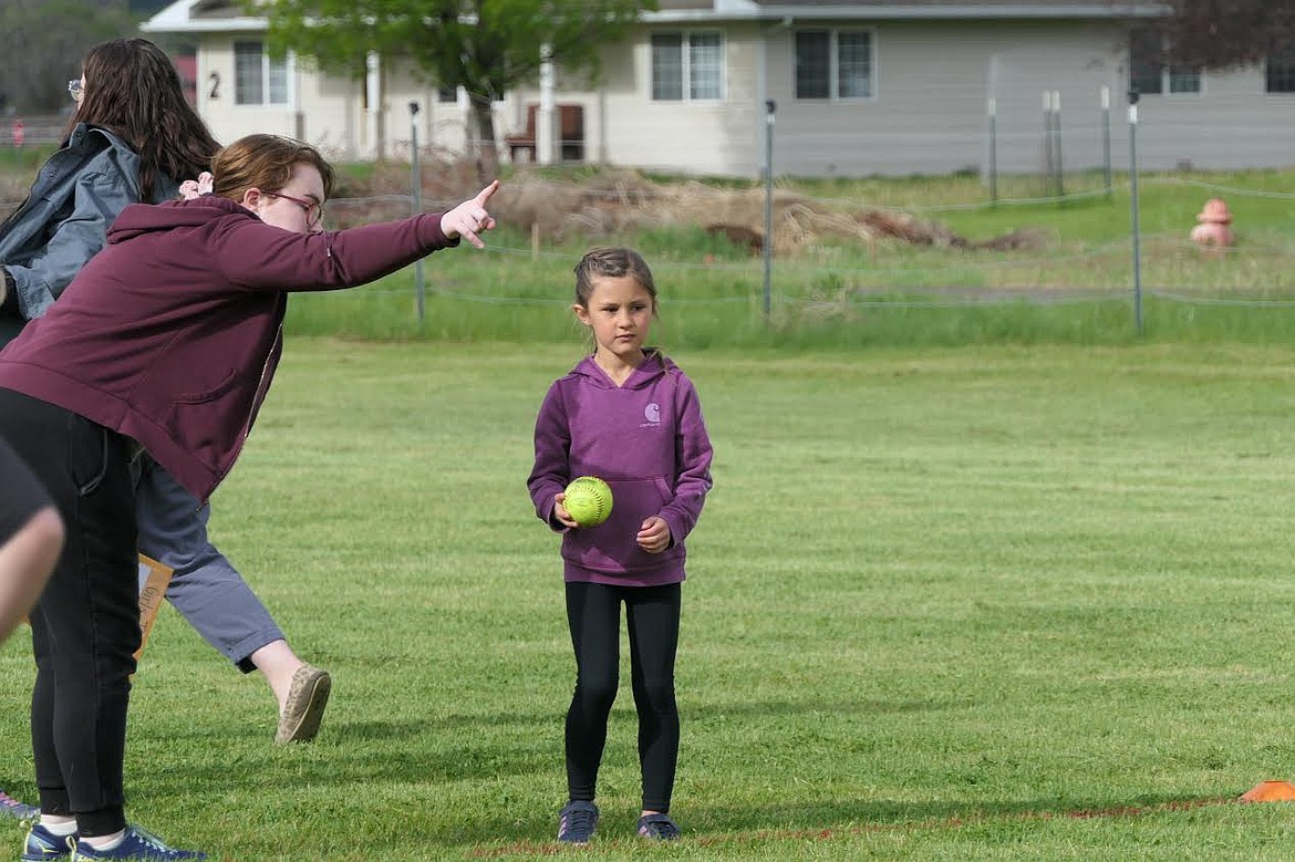 Plains kindergarten student Grace Larson receives instructions before throwing a softball at track and field day last Wednesday. (Adam Lindsay/Valley Press)