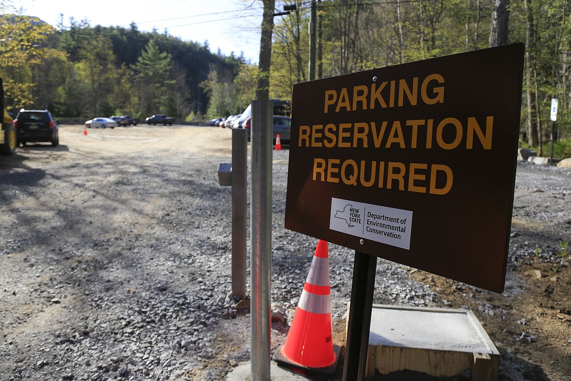 A parking reservation sign alerts visitors at the entrance to the Adirondack Mountain Reserve trailhead, Saturday, May 15, 2021, in St. Huberts, N.Y. A free reservation system went online recently to control growing numbers of visitors packing the parking lot and tramping on the trails through the private land of the Adirondack Mountain Reserve. The increasingly common requirements, in effect from Maui to Maine, offer a trade-off to visitors, sacrificing spontaneity and ease of access for benefits like guaranteed parking spots and more elbow room in the woods. (Julie Jacobson/Associated Press)