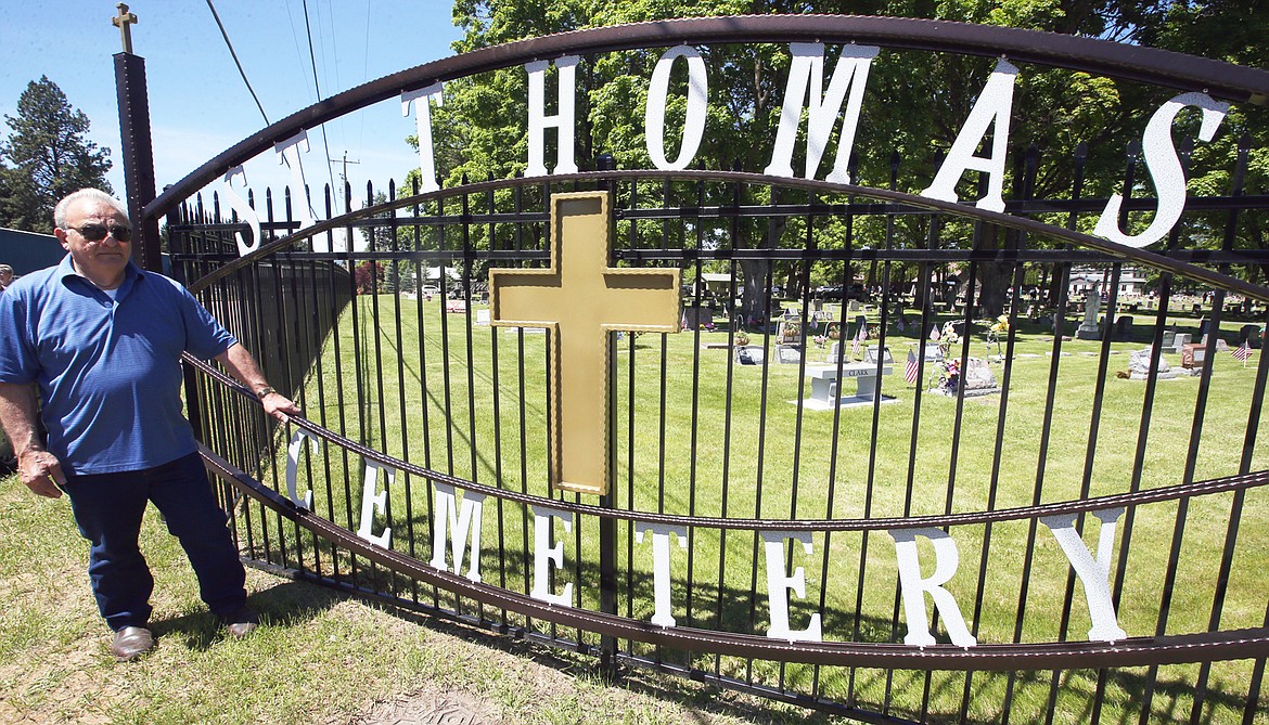 Ray Stongle of Hayden stands by the sign he designed and made at the southeast corner of St. Thomas Cemetery on Sunday.