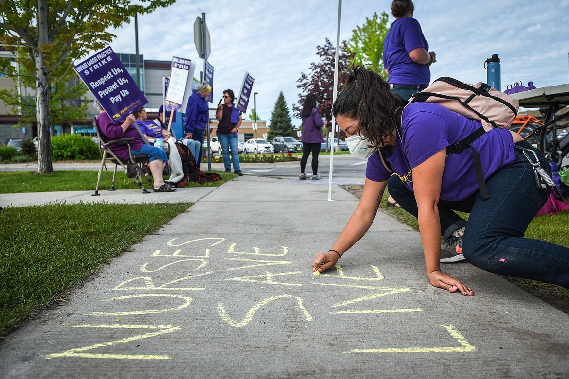 A nurses union supporter who wished to remain anonymous writes a message in chalk on the sidewalk during a strike outside Logan Health in Kalispell on Tuesday, June 1, 2021. (Casey Kreider/Daily Inter Lake)