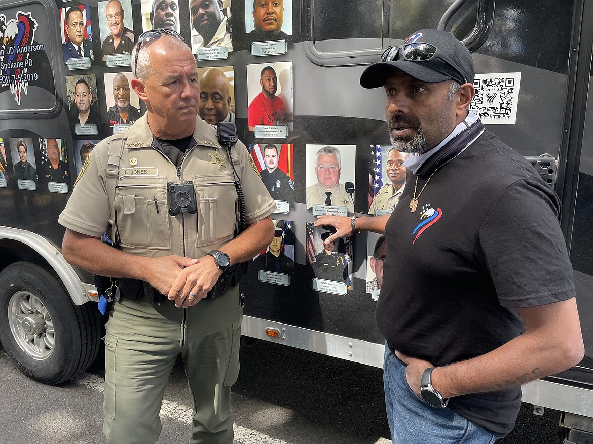 Jagrut Shah, head of the Beyond the Call of Duty Foundation, with Grant County Sheriff Tom Jones, in front of the photo of GCSO Deputy John Michael Melvin, who died of COVID-19 contracted while on the job in December 2020.