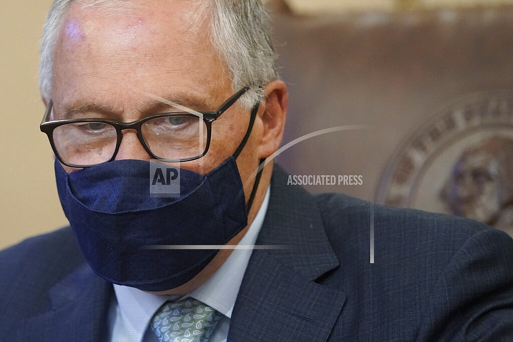 Washington Gov. Jay Inslee looks down at a stack of bills to be signed into law, Wednesday, May 12, 2021, at the Capitol in Olympia, Wash.