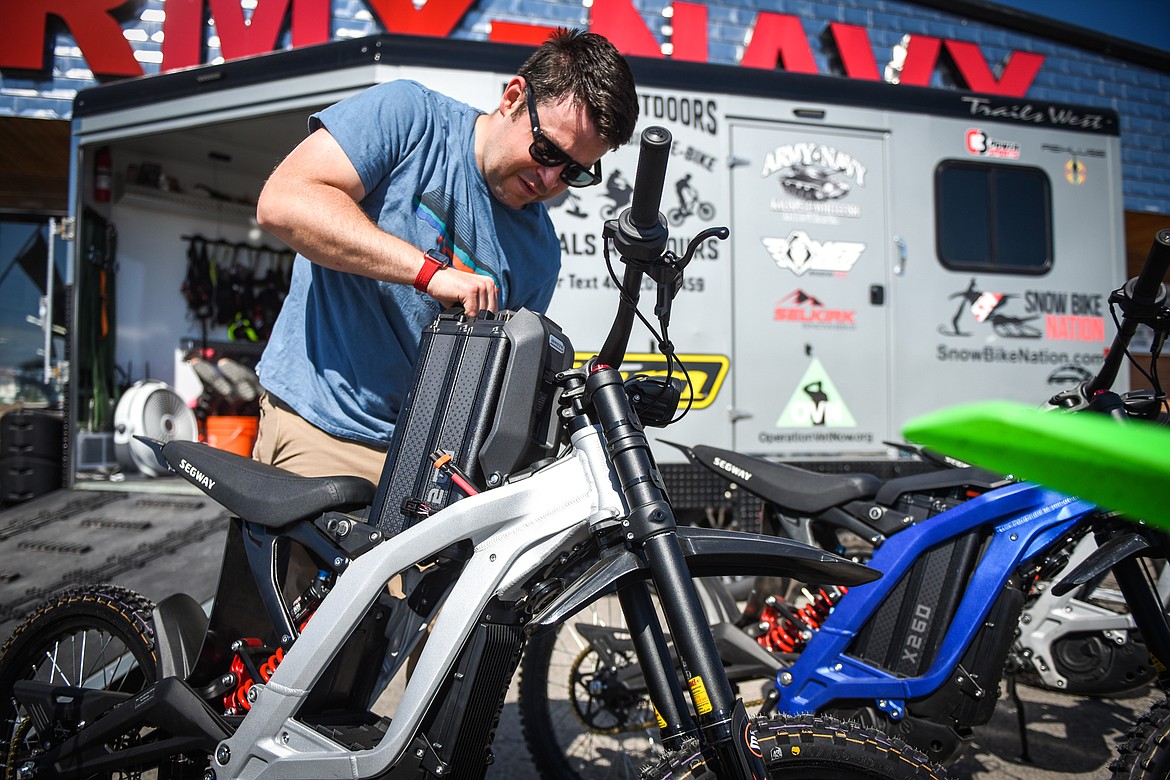 Garren Allred inserts a battery into an electric dirtbike on Friday, June 4. (Casey Kreider/Daily Inter Lake)