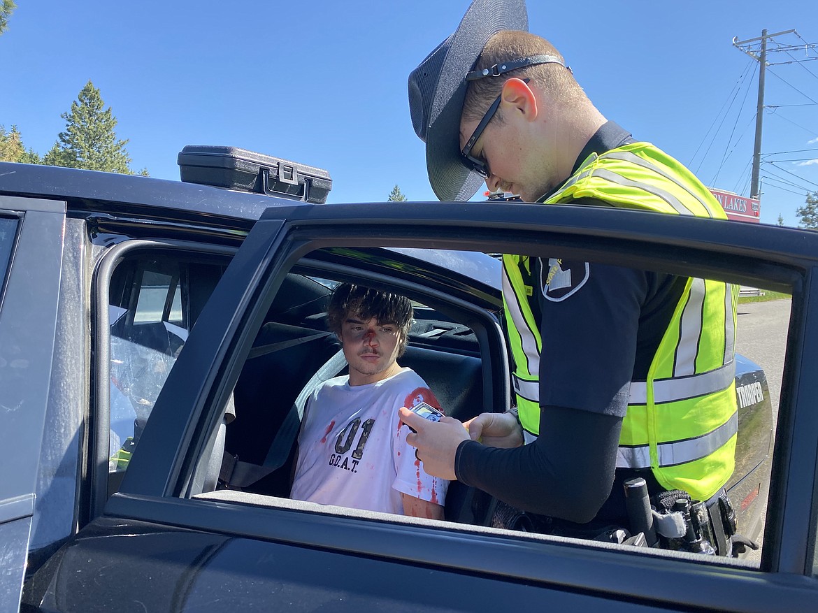 Senior Bryson Fisher, the designated drunk driver of Lakeland High School's mock DUI performance, is booked and put in the back of a cop car for his crime Friday morning. (MADISON HARDY/Press)