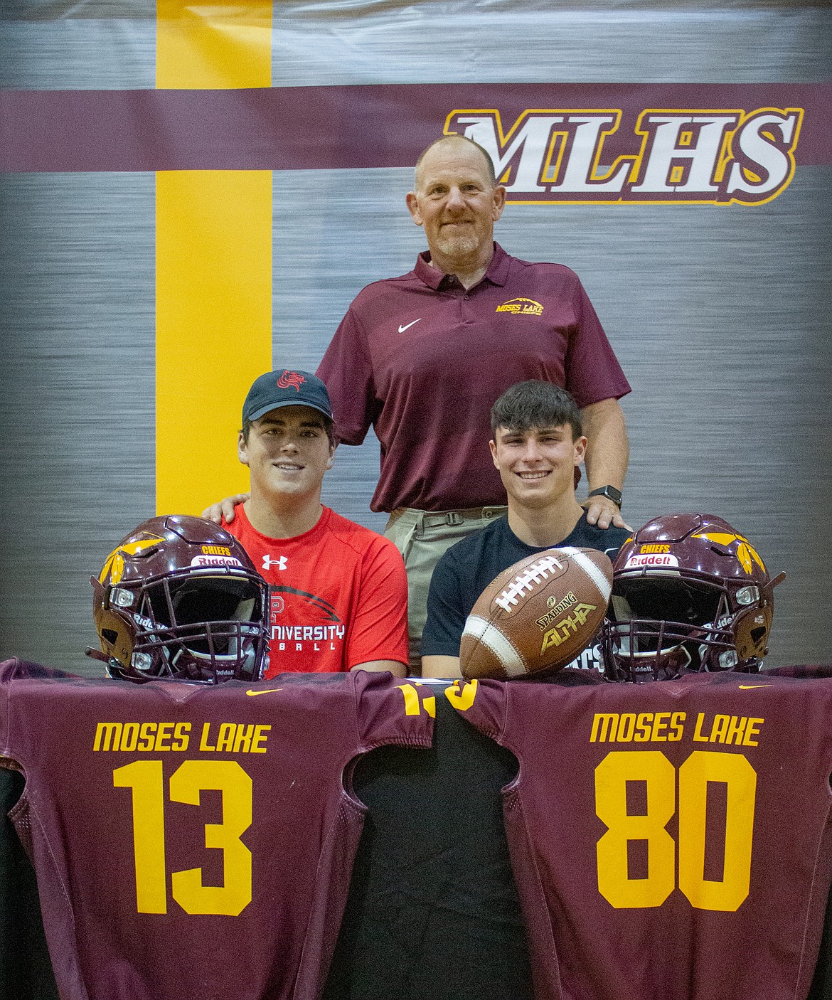 Left to right, Seniors Brandon Johnson, Coach Todd Griffith and Everett Ashley gather together for a photo in the Moses Lake High School gym on Friday afternoon to celebrate Johnson and Ashley signing to play football in college next season.