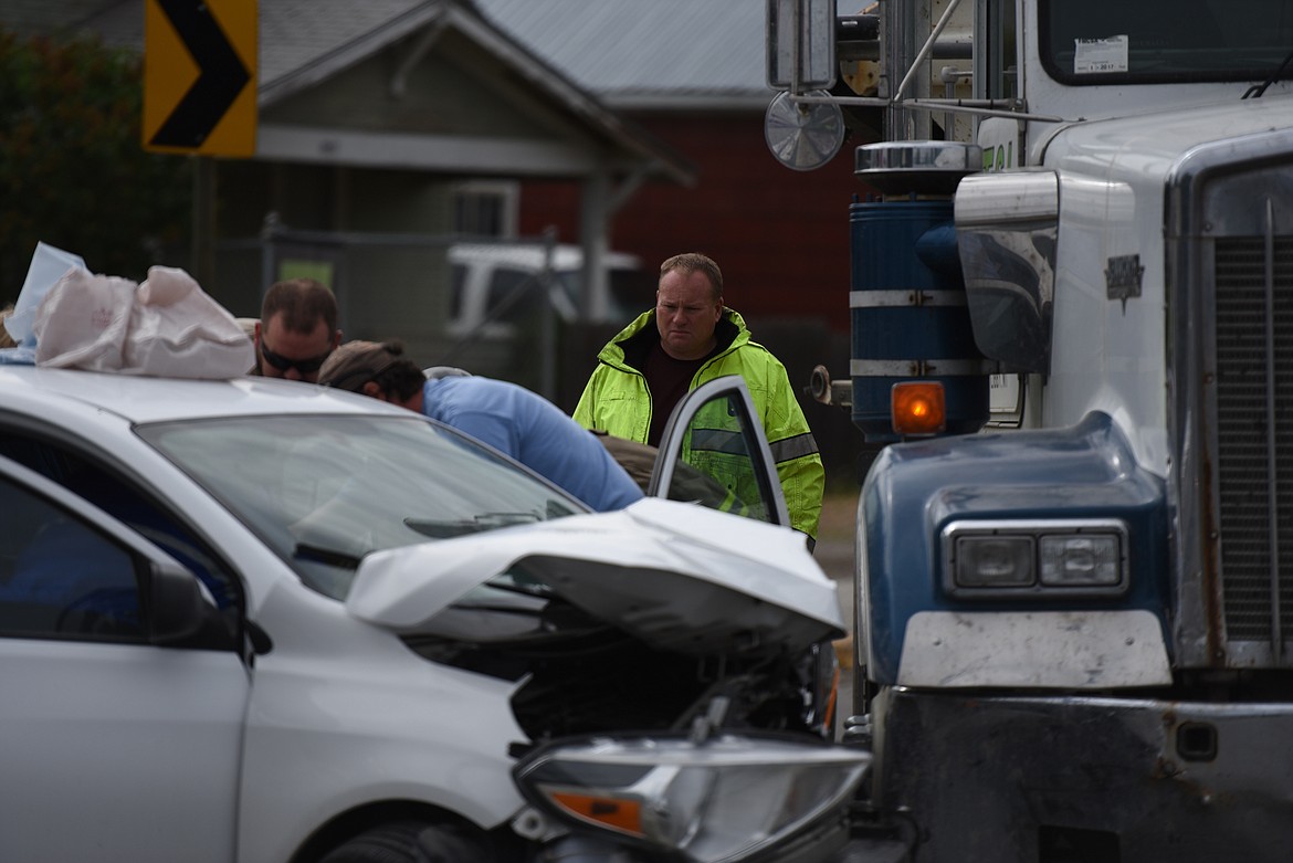 Scott Beagle of the Libby Volunteer Fire Department watches as paramedics treat a driver involved in a June 8 wreck at the intersection of U.S. Highway 2 and Minnesota Avenue. (Derrick Perkins/The Western News)