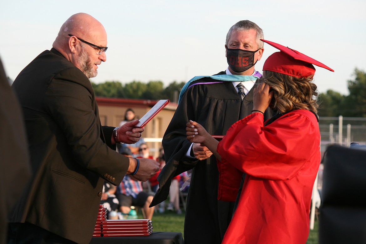 An Othello High School senior (right) receives her diploma from Othello School Board member Mike Garza (left) during graduation June 4.