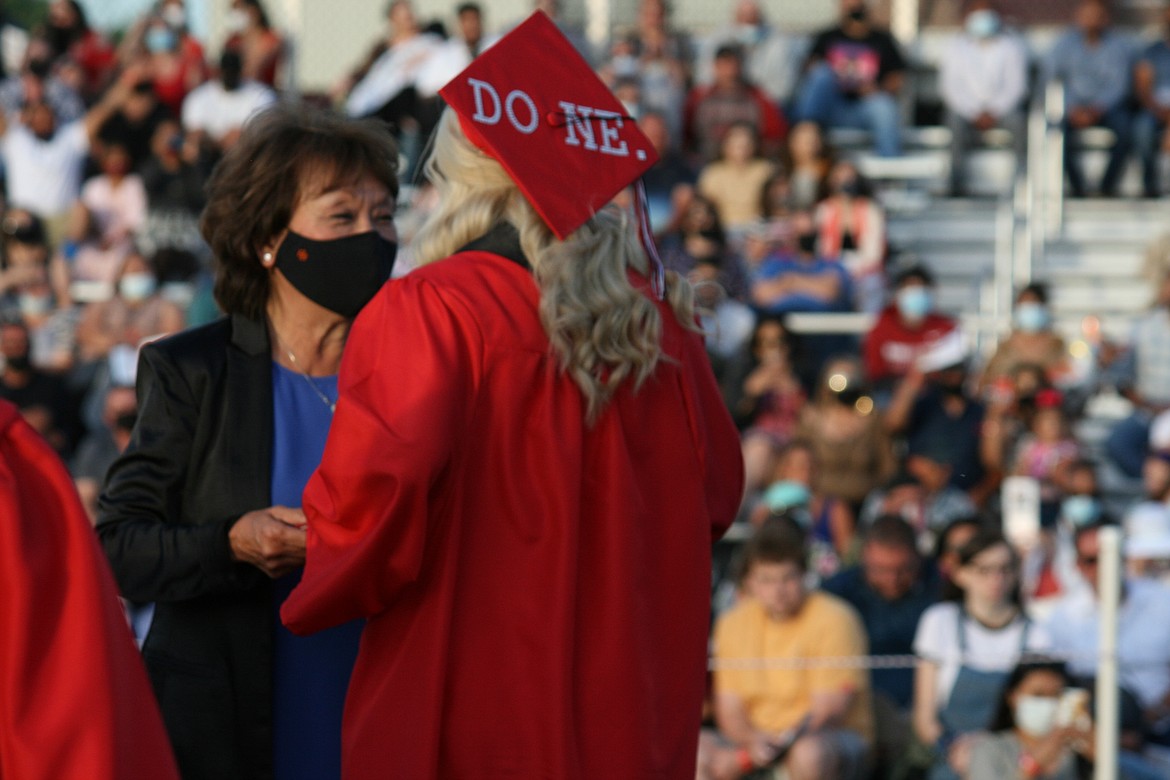 Othello School Board member Sharon Schutte (left) hands the diploma to Othello High School senior Ashley Garza, who used her graduation cap to proclaim her new status.