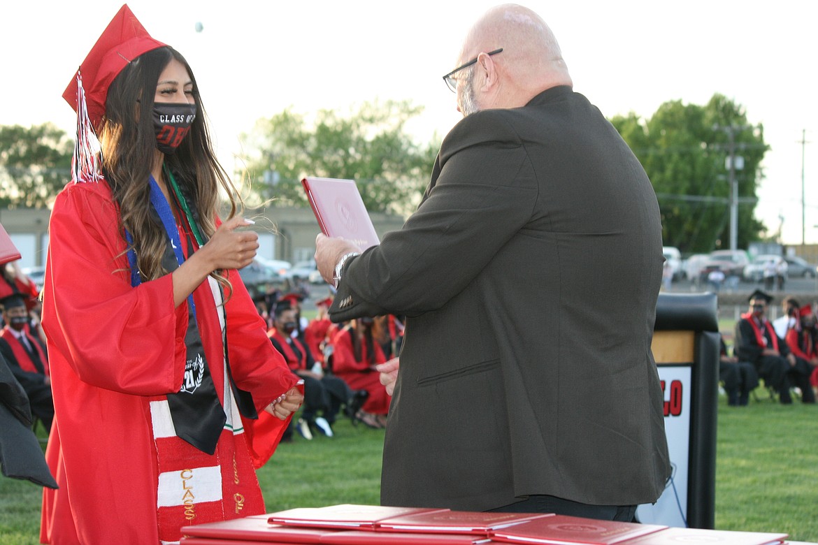 During graduation June 4, an Othello High School senior (left) receives her diploma from Othello School Board chair Mike Garza (right).