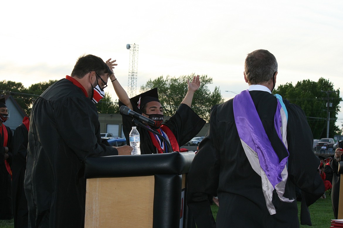 Senior Carlos Motta (center) is happy to get his diploma during Othello High School graduation ceremonies June 4.
