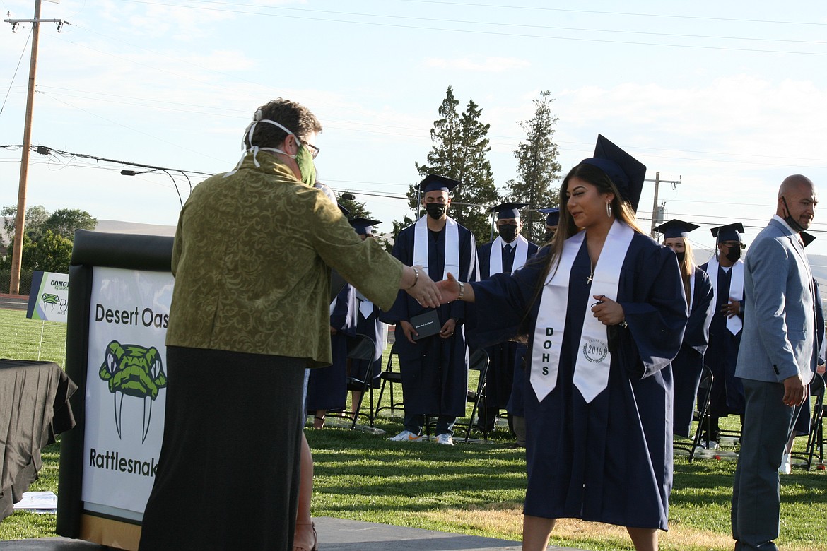 Othello School Board member Jenn Stevenson (left) shakes hands with a Desert Oasis High School senior during graduation ceremonies June 7 in Othello.