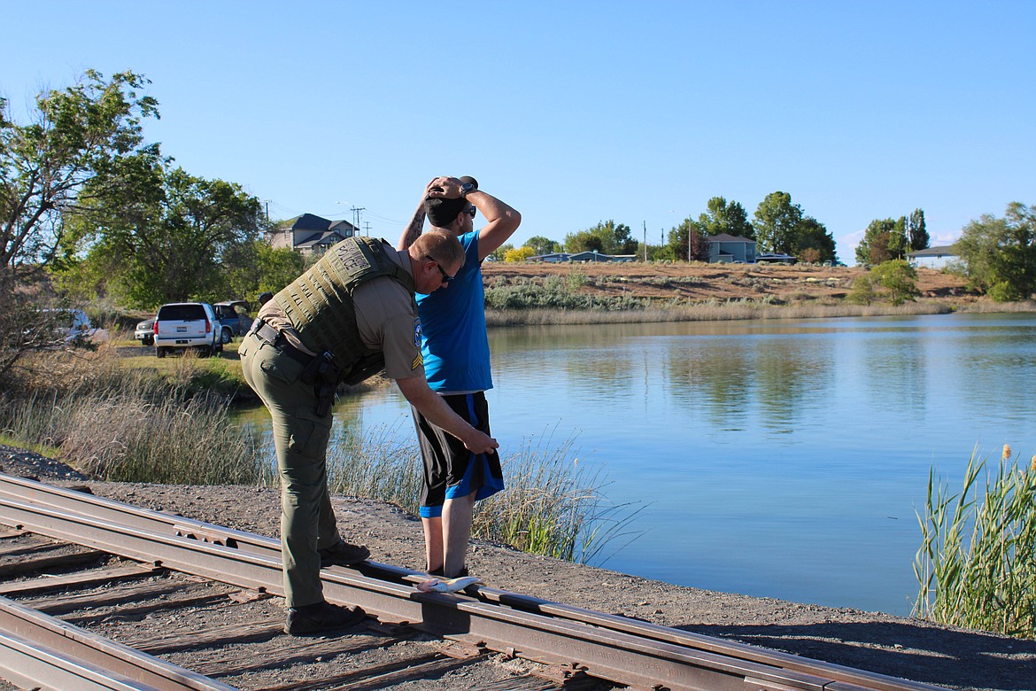 Sgt. Chris Busching pats down an angler in Moses Lake on Friday after discovering the man has three felony warrants.