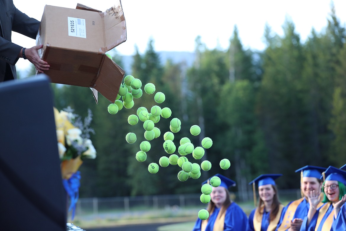 KC MacDonald dumps a box of tennis balls toward the grads.