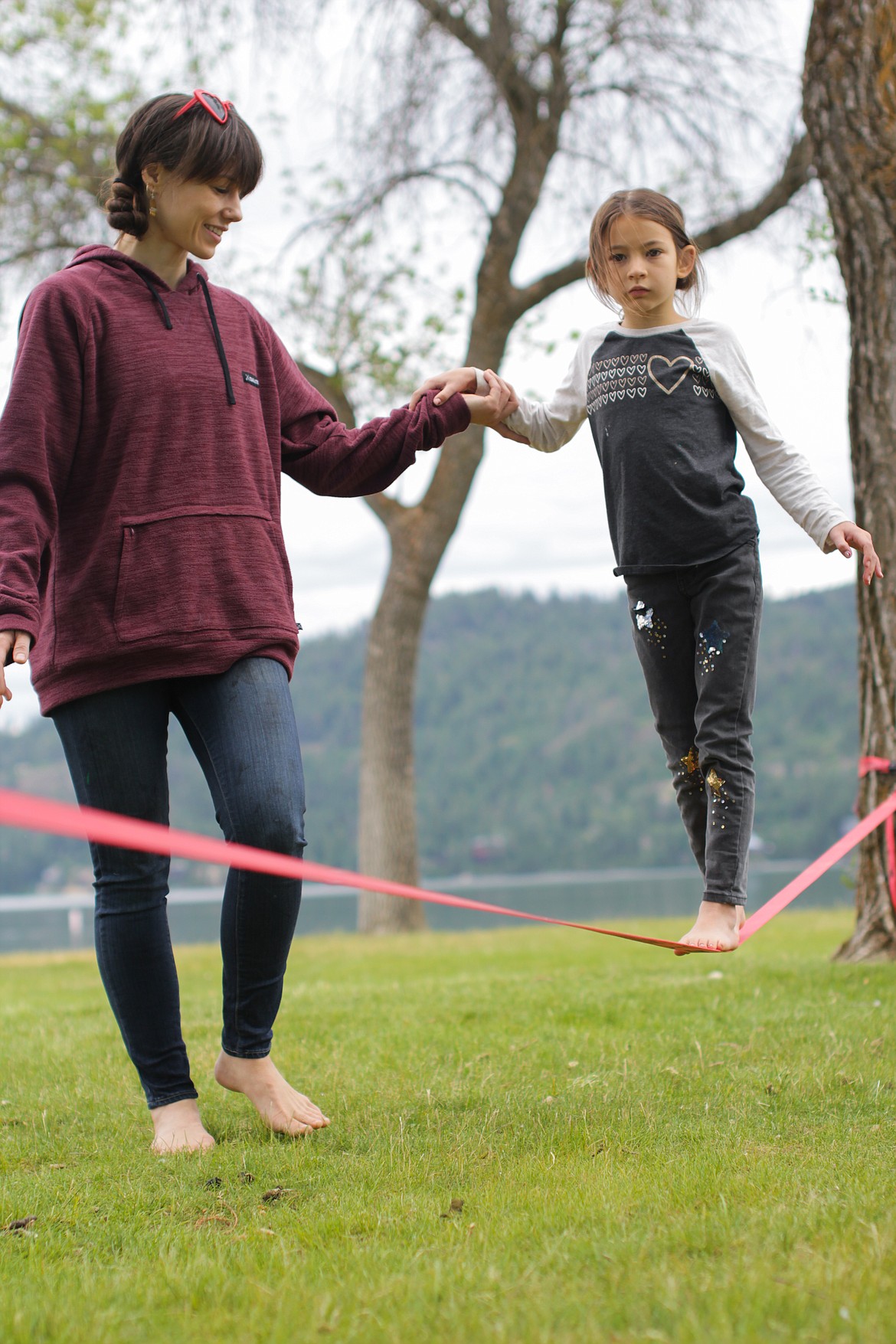 Lacey Raine Barlow helps Kiera Wilcox on a slackline at the annual Homeschool Academy party at City Beach Friday.