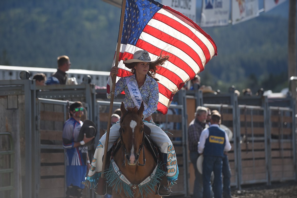 Real Cowboy Association Montana Pro Rodeo Queen Megan Tutvedt carries the U.S. flag while she rides around the arena before the Hot Springs Rodeo began last Saturday. (Scott Shindledecker/Valley Press)